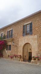 Rustic stone house with potted flowers and arched wooden door in countryside setting
