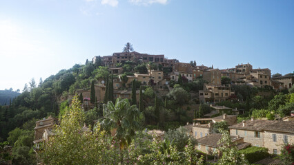Fototapeta premium Scenic view of deia village in mallorca showing traditional stone houses nestled among lush greenery under a clear blue sky