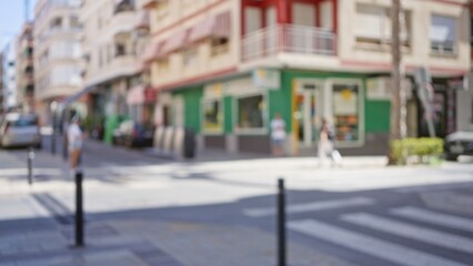 Blurred outdoor street scene with defocused buildings and people including man and woman walking on a sunny day with vibrant colors