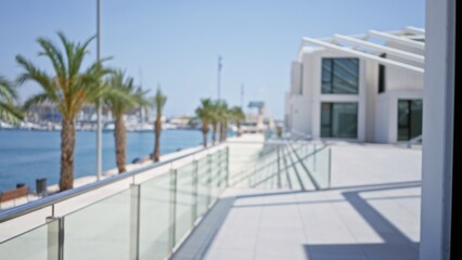Sunny seaside promenade lined with palm trees and modern architecture, defocused background featuring a clear blue sky and marina view, perfect for vacation and travel themes.