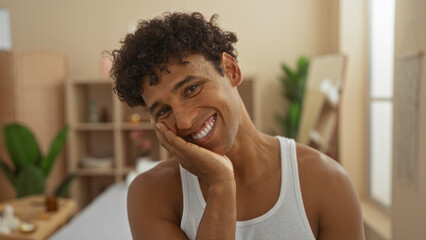 Young man smiling warmly in a tranquil spa room with elegant decor, showcasing wellness and beauty...