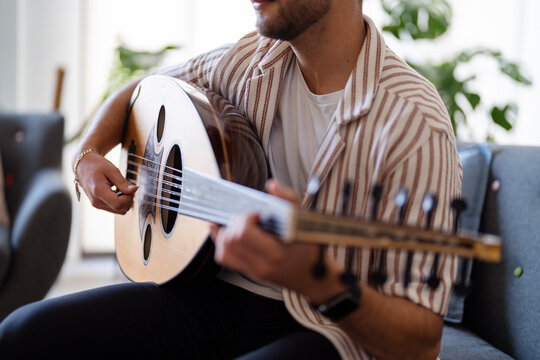 man&rsquo;s hand skillfully strumming the strings of an oud, capturing the intricate design of the instrument and highlighting the delicate craftsmanship and cultural significance of the musical tradition.
