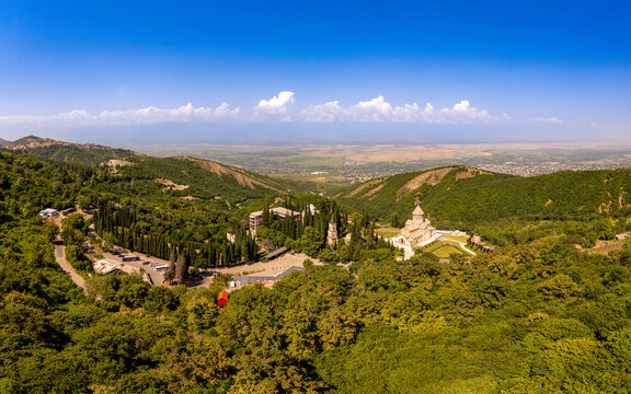 Aerial top view of the Bodbe Monastery architectural complex of St. Nino. View from above to church, Alazani Valley, Greater Caucasus mountains, in sunny summer day. Sighnaghi city, Kakheti, Georgia.