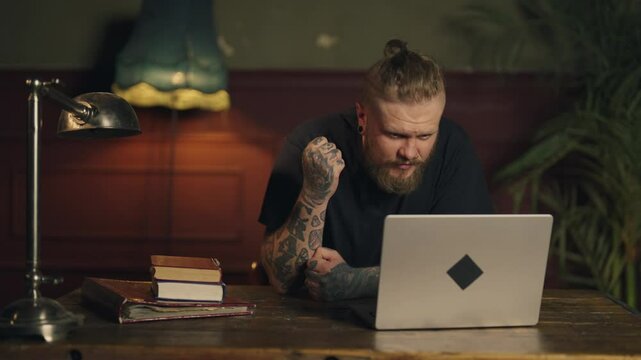 Soccer fan watching games on laptop at home in evening, emotional man portrait. Expressive male viewer shouting on screen, gesticulate by hands, online streaming service on web site, internet addict