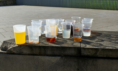 Backlit morning view of plastic cups with drinks abandoned on a railing after Saturday night