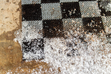 Dirty entrance mat. Cleaning shoes from dirt. Snow and ice on outdoor mat. Natural