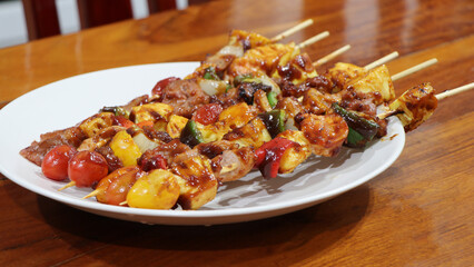 Close up BBQ grills at barbecue party on white dish at countryside in holiday. Grilled vegetables and chicken meat skewers grilled on table, appetizing.