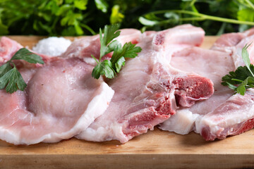 Fresh uncooked pork chops on wooden table. Close up