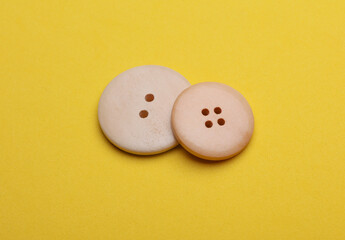 Wooden buttons on a yellow background close up