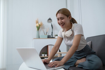 A woman is sitting on a couch and using a laptop