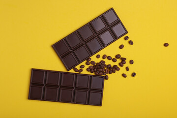 Dark chocolate bars with coffee beans on yellow background