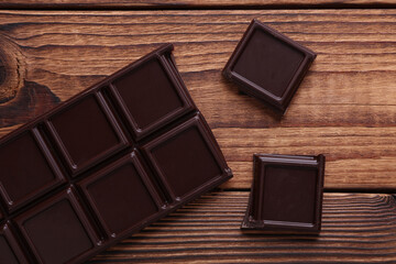 Blocks of broken chocolate bar on wooden background