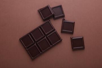 Blocks of broken chocolate bar on brown background