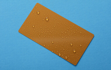 Golden business card with water drops on blue background