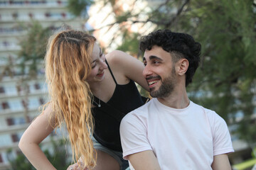 Obraz premium portrait of cute cheerful couple looking at each other laughing at the park on summer day