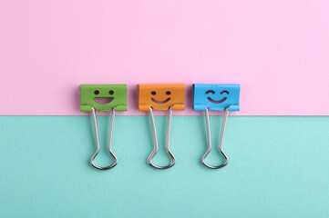 Binder clips with a smiling face on pink blue background