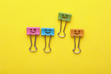 Binder clips with a smiling face on yellow background. Business concept. Creative layout