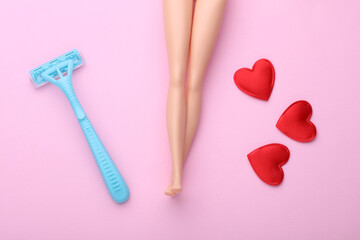 Legs of doll with razor and hearts on a pink background. Depilation. Minimalism