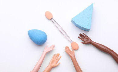 Doll's hands holding makeup accessories on white background