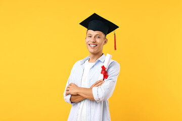 Happy student with diploma after graduation on orange background