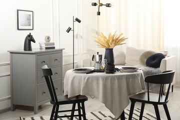 Stylish table setting with beautiful dishware and black chairs in dining room