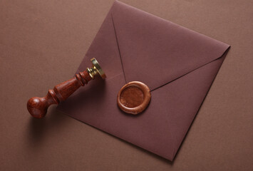 Envelope with wax seal and vintage stamp on brown background. Gift certificate, wedding invitation