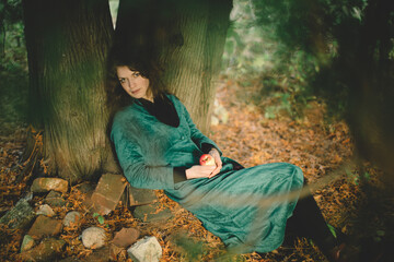 Woman in Green Resting Beneath a Tree with Apple