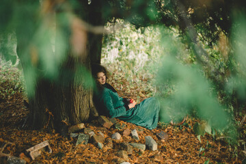 Woman in Green Resting Beneath a Tree with Apple