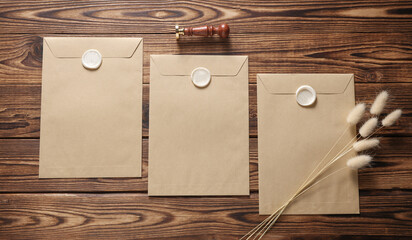 Envelopes with wax seals and vintage stamp, dry flowers on wooden background. Gift certificate,...