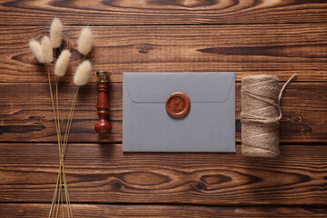 Envelope with wax seals and vintage stamp, thread, lagurus flowers on wooden background. DIY, Gift...