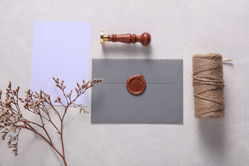Envelope with wax seal and vintage stamp, thread, dry flowers on gray background. DIY, Gift...