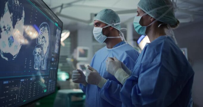Portrait of a Female Surgeon Closely Studying Brain Imaging on a Big Screen, Collaborating with Her Team Member to Finalize the Plan for an Important Surgical Procedure in a Modern Clinic