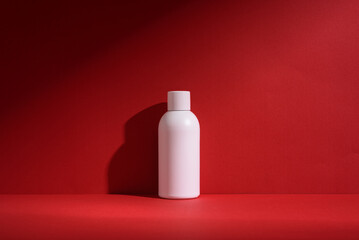 Minimalistic white cosmetic bottle mockup with shadows on a red background