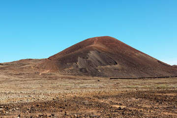 Wonderful volcanic landscape of Volcano Calderon Holdo with rocky surface located in dry valley under blue sky near to Corralejo. La Olivia, Fuerteventura. Spain