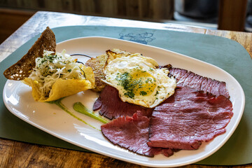 Grilled mountain salted meat served with a fried egg, potato tortel and a Trentingrana basket with cabbage salad