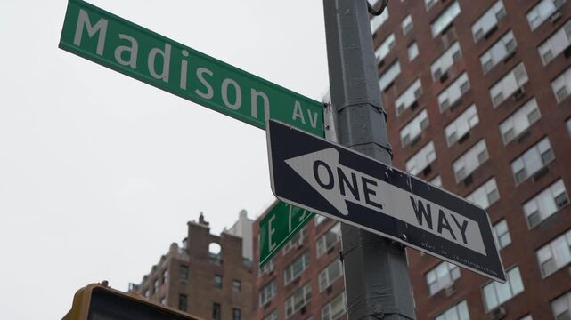 A street sign positioned at the bustling intersection of Madison Avenue and East 79th Street within a city layout