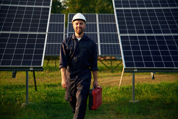 Red case in hand. Man is working with solar panels outdoors at daytime