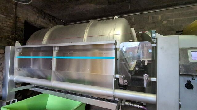 Automatic grape pressing procedure. Pneumatic press machine extracts grape juice which goes to the barrels for wine production .