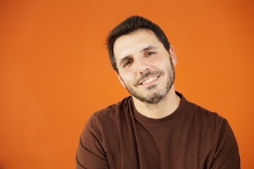 Obraz premium Young handsome guy isolated on orange background. Smiling at the camera, he is very happy, he is happy with the life he has.