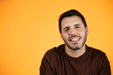 Young handsome guy isolated on orange background. Smiling at the camera, he is very happy, he is happy with the life he has.