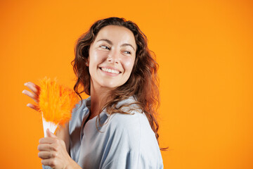 Portrait of young woman on orange background. Isolated woman. She holds a fan in her hand because she is hot.