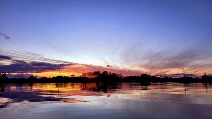 Beautiful sunset on the lake in lilac and pink tones, golden evening sun