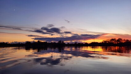 Obraz premium Beautiful sunset on the lake in lilac and pink tones, golden evening sun