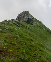 MOuntain ridge with steep slopes covered by grass and rocky hill summit in Alpi Graie mountains in Italy