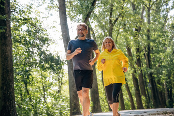 Fototapeta premium Front view, jogging, sports. Senior couple together outdoors at nature