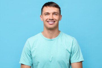 Smiling man with dental braces on light blue background