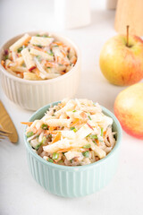 Asian Apple Slaw Salad with Apples, cabbage, carrot and spring onions. Healthy fall vegetable salad with yogurt dressing, in portioned bowls on kitchen table 