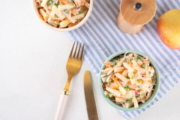 Asian Apple Slaw Salad with Apples, cabbage, carrot and spring onions. Healthy fall vegetable salad with yogurt dressing, in portioned bowls on kitchen table 