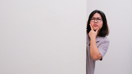 A woman peeking out from behind a wall showing confused expression