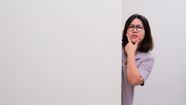 A woman peeking out from behind a wall showing confused expression